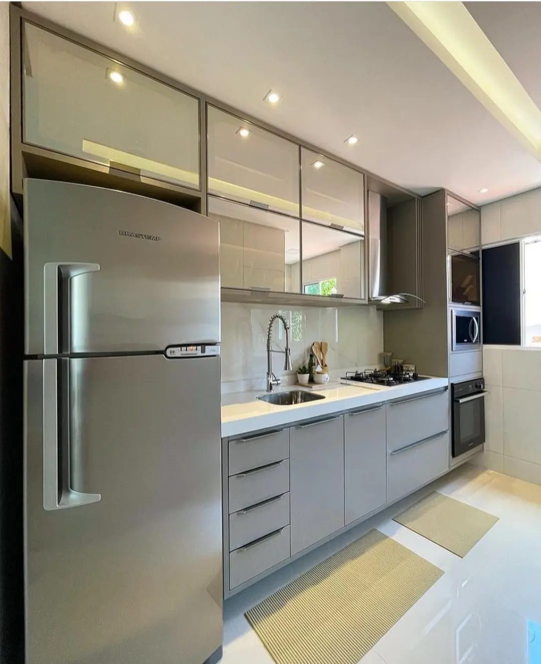 Cozinha corredor com armários fendi, aéreos de vidro e geladeira embutida