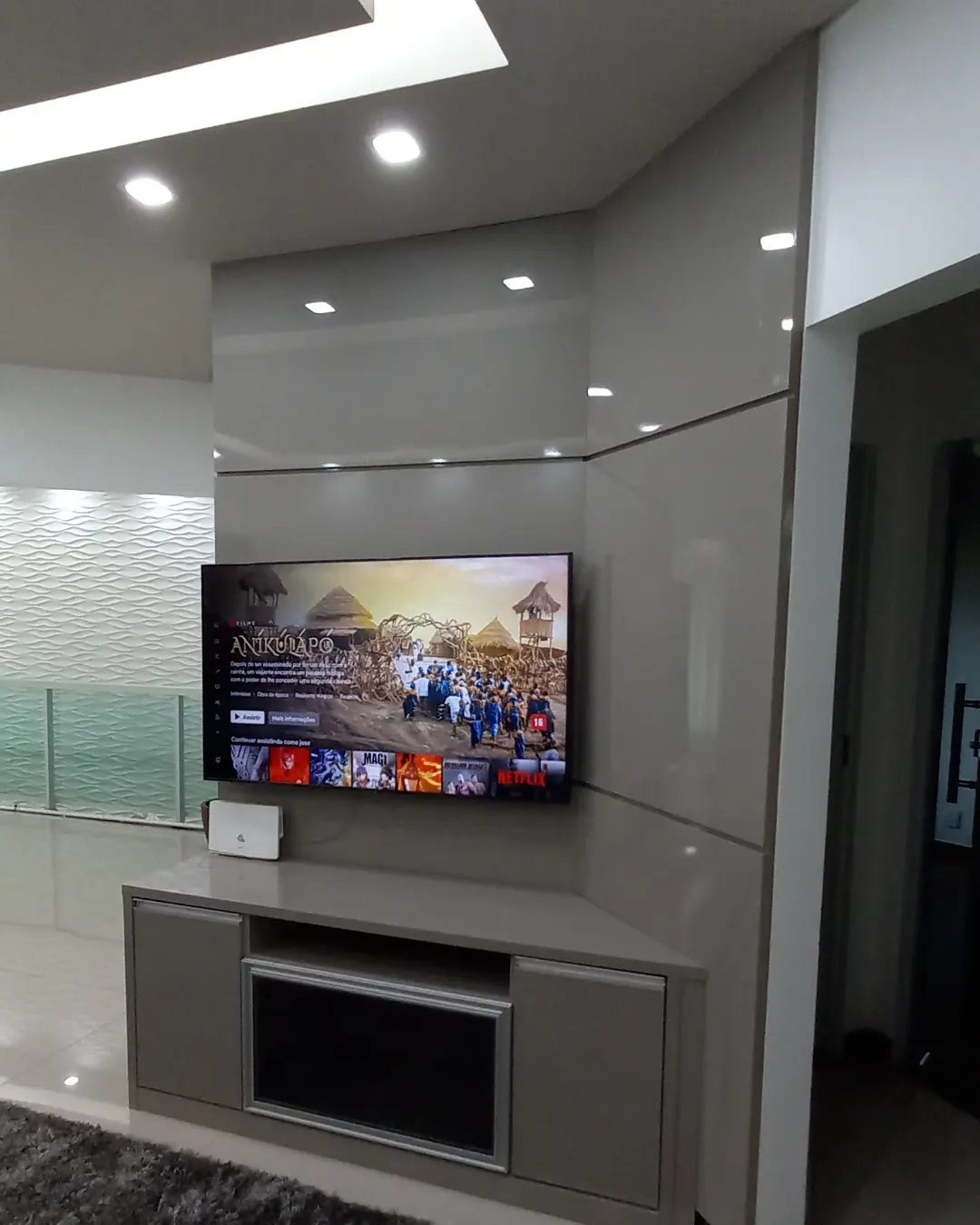 Sala com painel de laca fendi do chão ao teto e rack com nicho