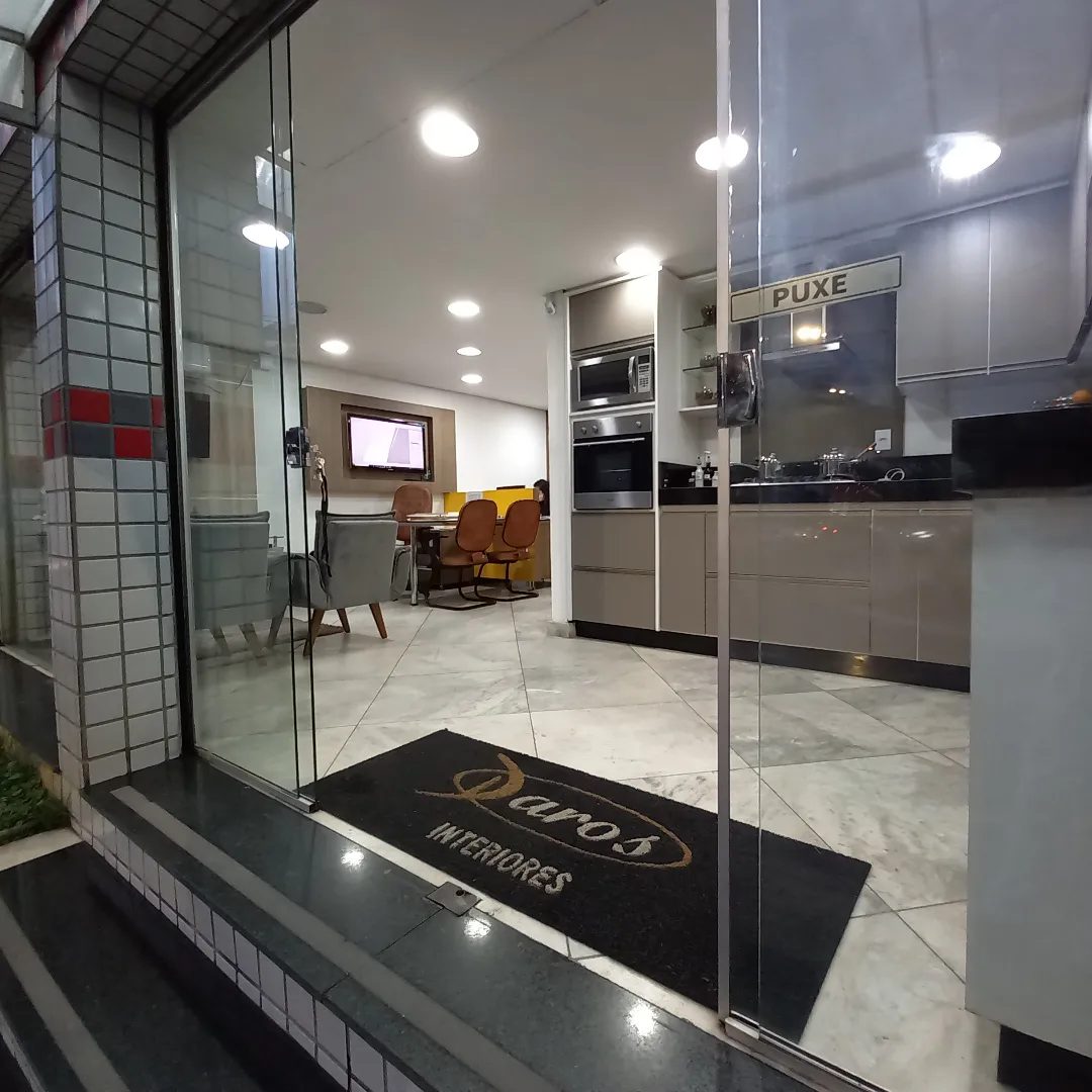 Entrada do showroom da Daros, com o tapete da marca e uma cozinha montada ao fundo